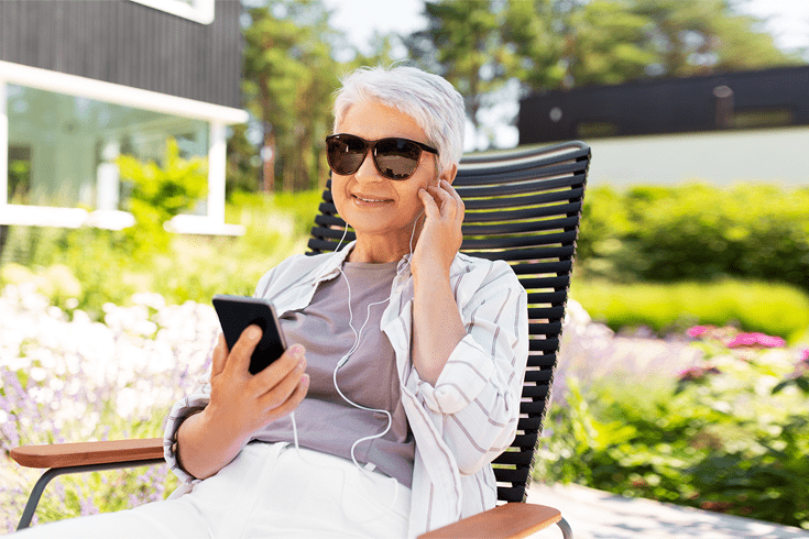 woman listening to podcast in garden