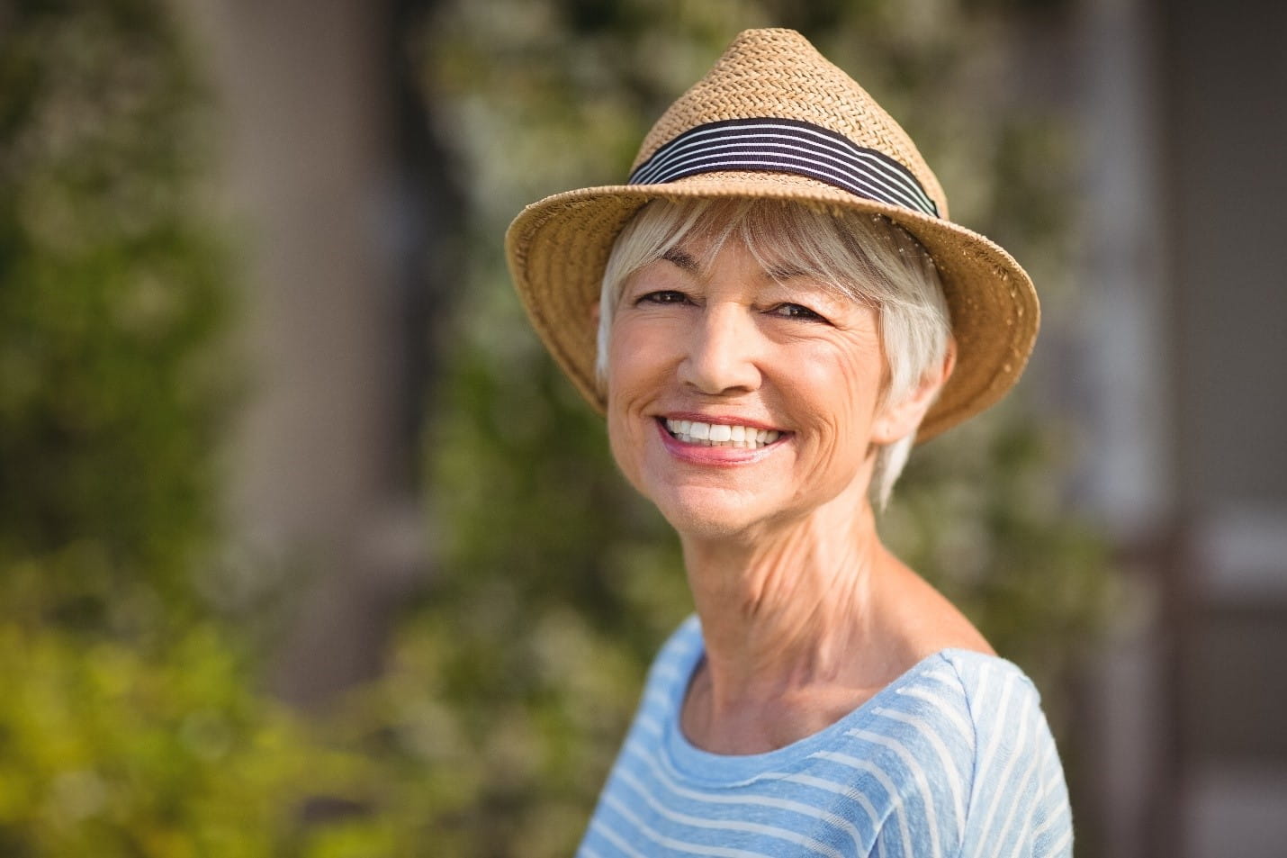 Senior woman smiles at camera while standing outside.