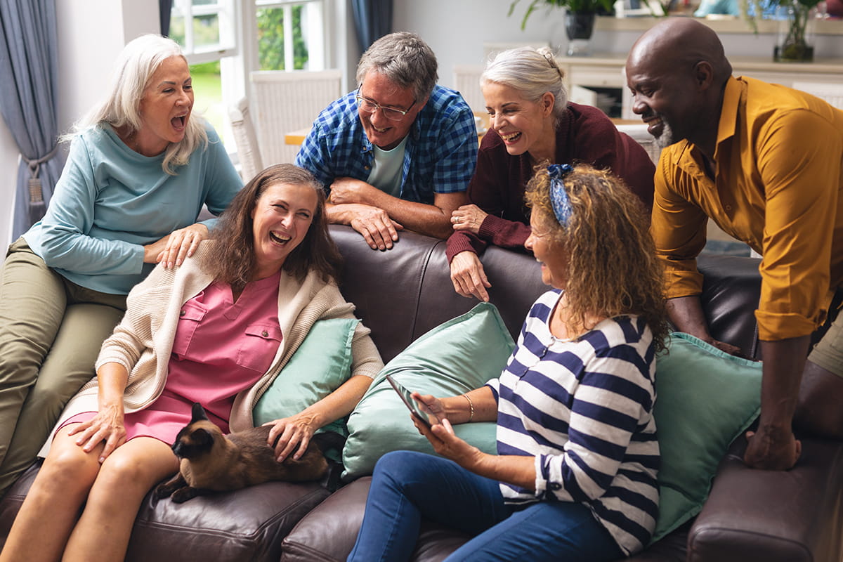 Group of seniors laugh together on a couch.